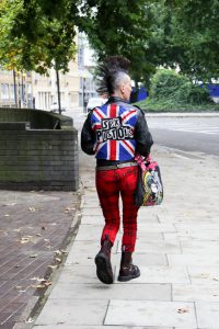 London, England - October 06, 2008: Punk Rocker Girl with a Sex Pistols jacket and a Mohican hairstyle with shaved sides of her head walks down a London Street